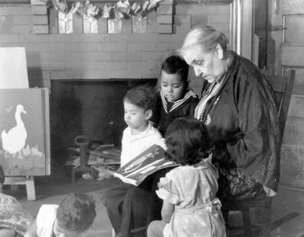 Photograph of Jane Addams reading to children at Hull House.