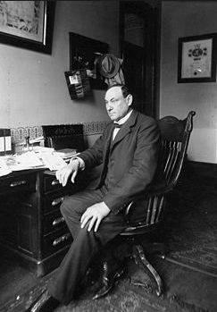 Photograph of Harvey Wiley sitting at desk, ca. 1900.