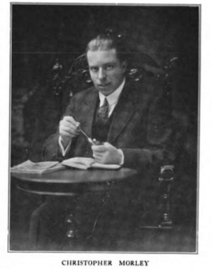 Portrait photograph of Christopher Morley sitting at a table, ca. 1918.