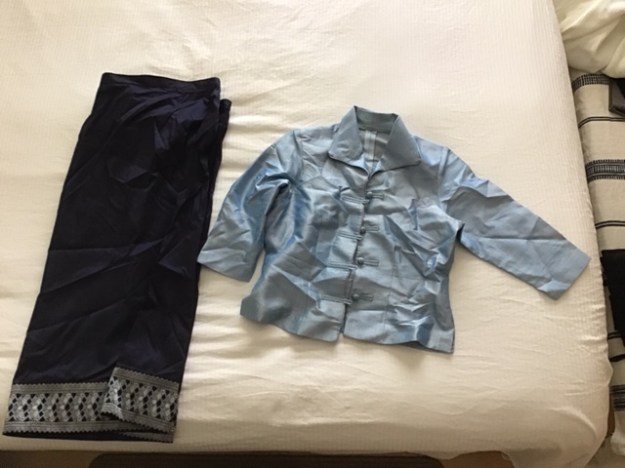 Wrinkled Lao blouse and skirt on bed.